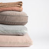 Harlow Blanket | stack of cotton velvet living pieces: throw blanket in rouge, 18" round pillow in fog, 18" square in cloud and 24" square pillow in pearl straight on against a white background.  The different trim details visible on each piece.