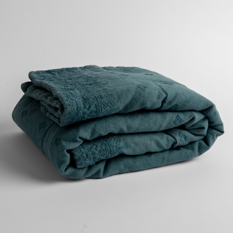 Ines Baby Blanket | Cenote | embroidered linen baby blanket folded and shown  overhead from a slight angle against a white background.