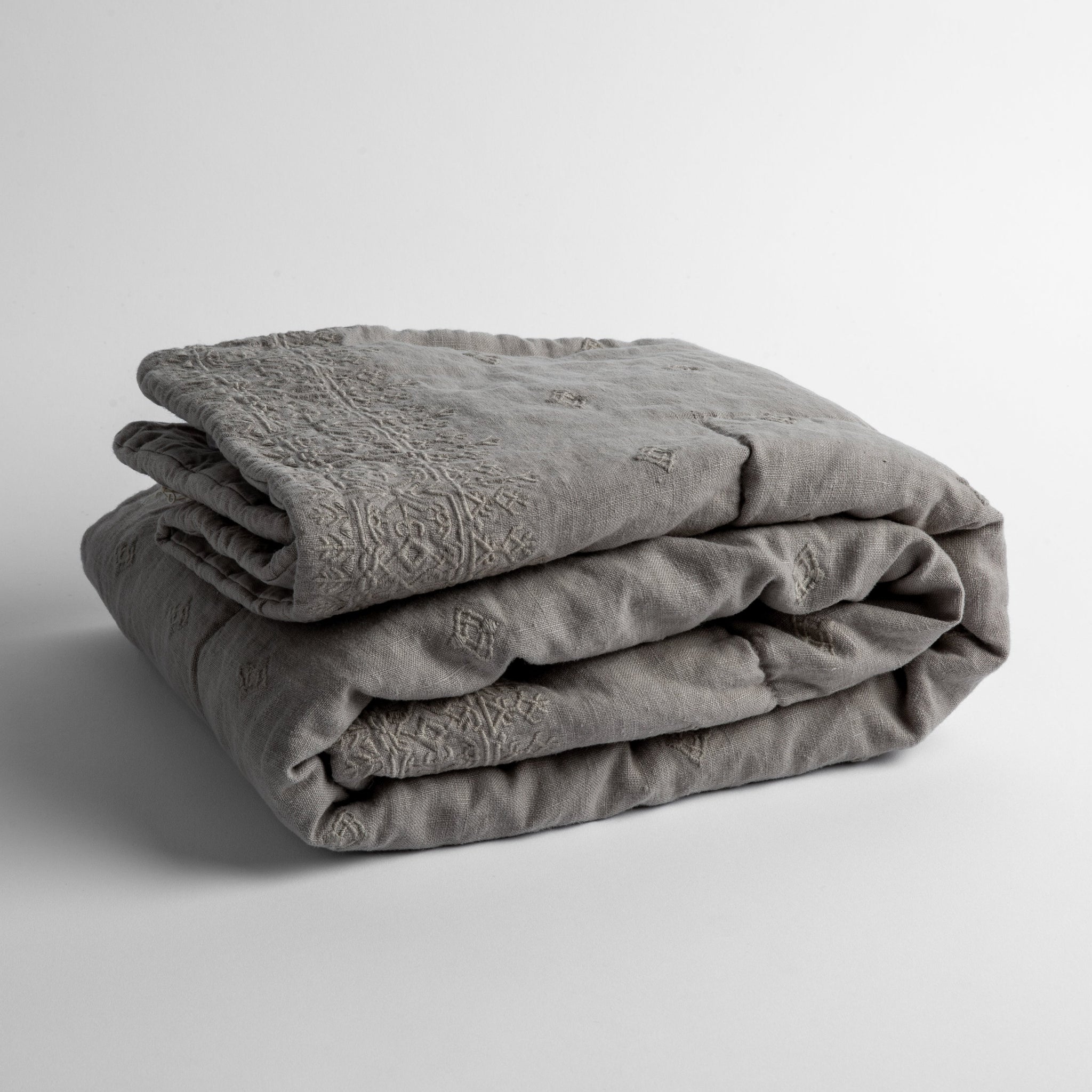 Ines Baby Blanket | Fog | embroidered linen baby blanket folded and shown  overhead from a slight angle against a white background.