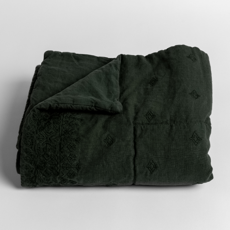 Ines Baby Blanket | Juniper | embroidered midweight linen baby blanket folded with the corner folded back to reveal its unembroidered linen back.