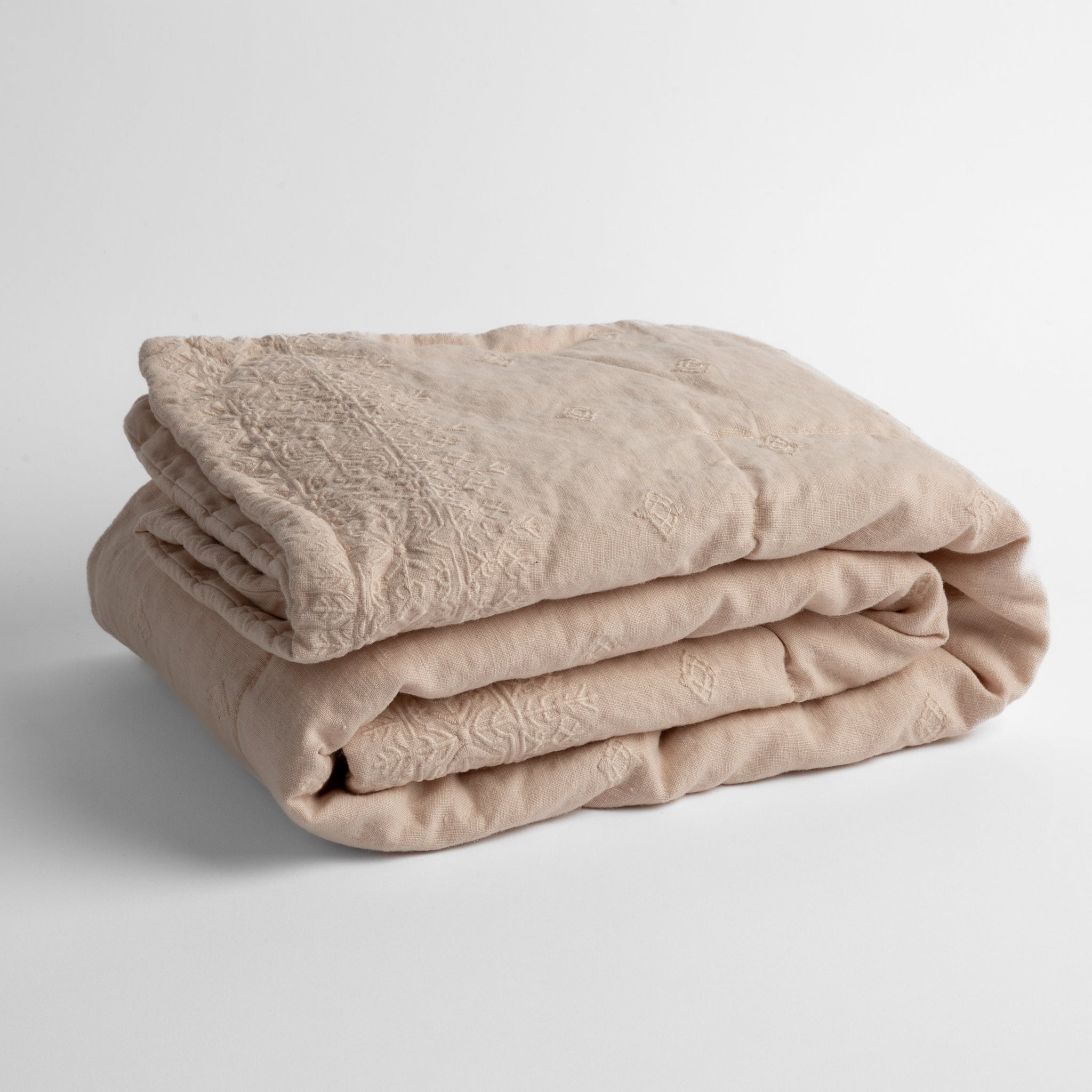 Ines Baby Blanket | Pearl | embroidered linen baby blanket folded and shown  overhead from a slight angle against a white background.