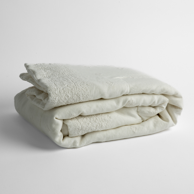 Ines Baby Blanket | Winter White | embroidered linen baby blanket folded and shown  overhead from a slight angle against a white background.