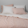 Ines Bedspread | Pearl | Bedspread with matching shams on a bed with white sheets and sleeping pillows. Shot from the end of bed view, the flat sheet is pulled back over the top of the bedspread.