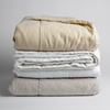 Ines Blanket | three Ines embroidered midweight linen bed end sized blankets stacked against a white background. Blankets shown in Parchment, Winter White and Fog