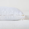 Ines Throw Pillow | White | Close-up of brass zipper and charmeuse pull details on throw pillow - side view.