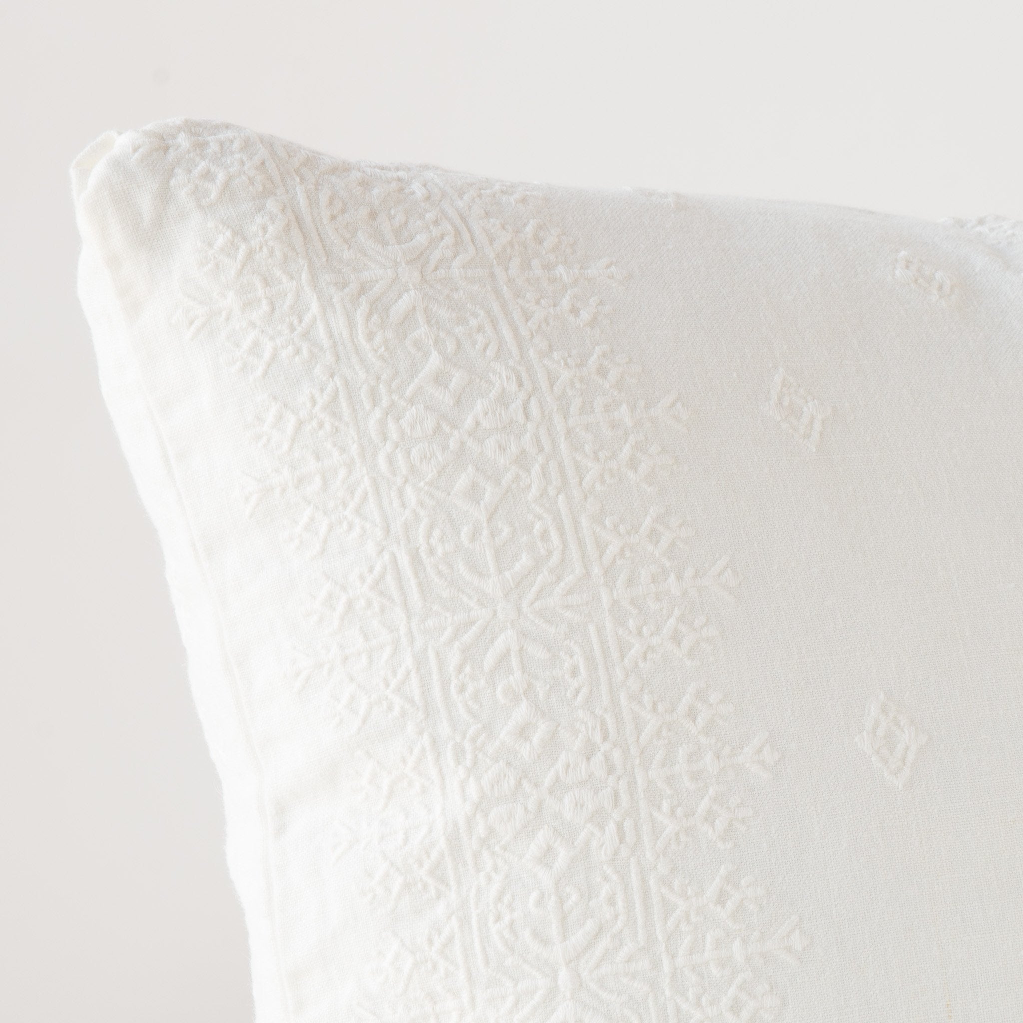 Ines Throw Pillow | Winter White | Close-up of pillow corner, showcasing the embroidery pattern detail.