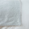 Ines Blanket | Cloud | Close-up of corner against a white background, showcasing embroidery pattern detail - overhead view.