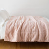Ines Blanket | Ines throw blanket in rouge, draped over a simple white bed - side view.