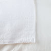 Ines Blanket | White | Close-up of corner against a white background, showcasing embroidery pattern detail - overhead view.