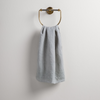 Ines Guest Towel | Cloud | guest towel draped through a decorative brass towel ring against a white background.