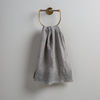Ines Guest Towel | Mineral | guest towel draped through a decorative brass towel ring against a white background.
