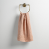Ines Guest Towel | Rouge | guest towel draped through a decorative brass towel ring against a white background.