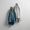 Two Ines guest towels, draped over decorative hooks against a white wall - cenote and cloud.