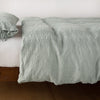 Ines Duvet Cover | Eucalyptus | lightly rumpled duvet cover on a monochromatic bed against a white background - side view.