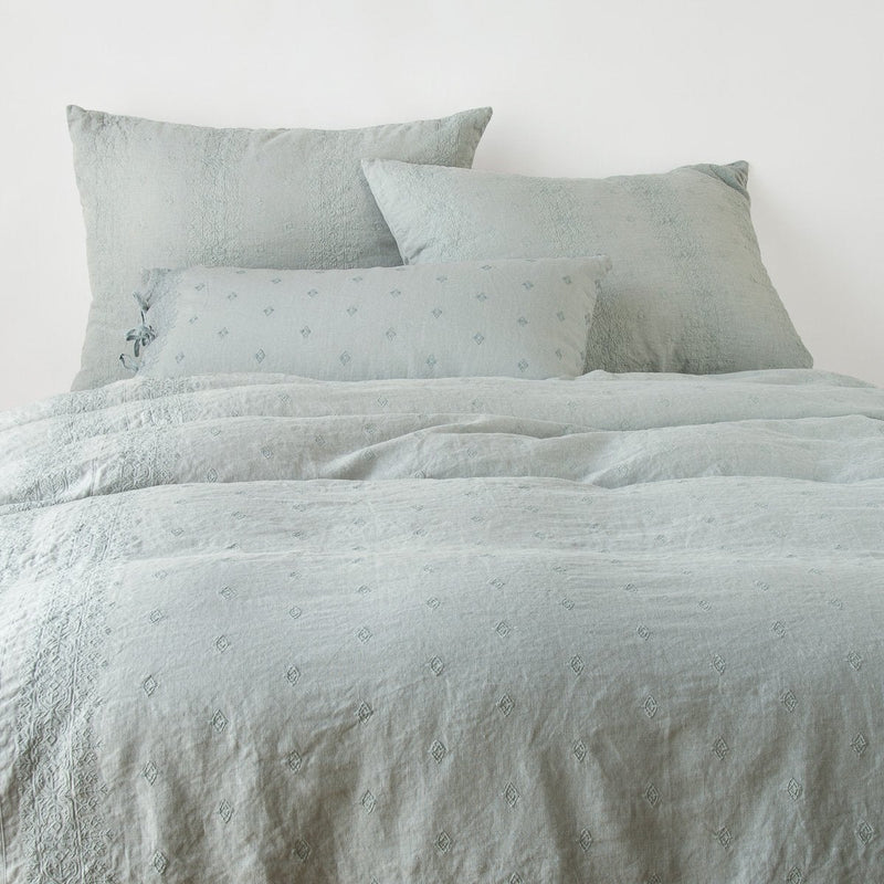 Ines Duvet Cover | Eucalyptus | duvet cover and matching shams against a white wall - end of bed view.