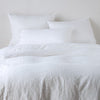 Ines Duvet Cover | White | duvet cover and matching shams against a white wall - end of bed view.