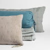Ines Throw Pillow | embroidered midweight linen throw pillows and folded bed end sized throw blanket with linen bolster straight on against a white background.