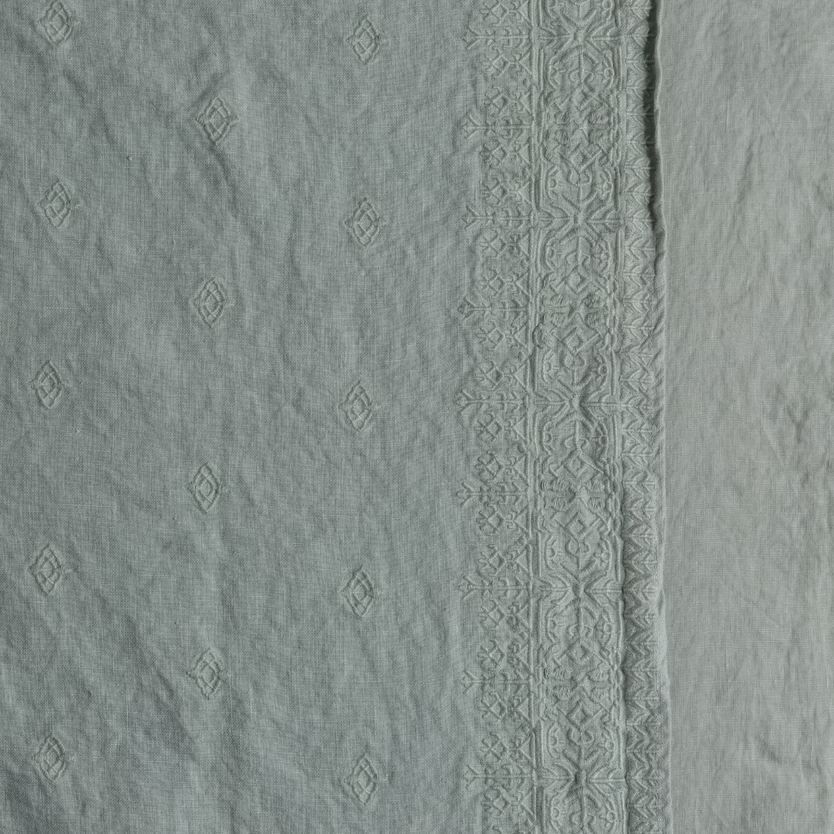 Ines Baby Blanket | Eucalyptus | A close up of embroidered midweight linen fabric in eucalyptus, a soft light green.
