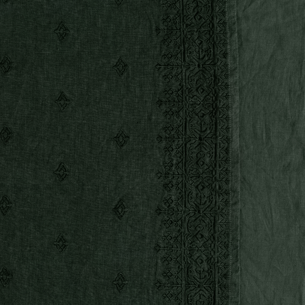 Ines Bedspread | Juniper | A close up of embroidered midweight linen fabric in Juniper, a deep green tone.