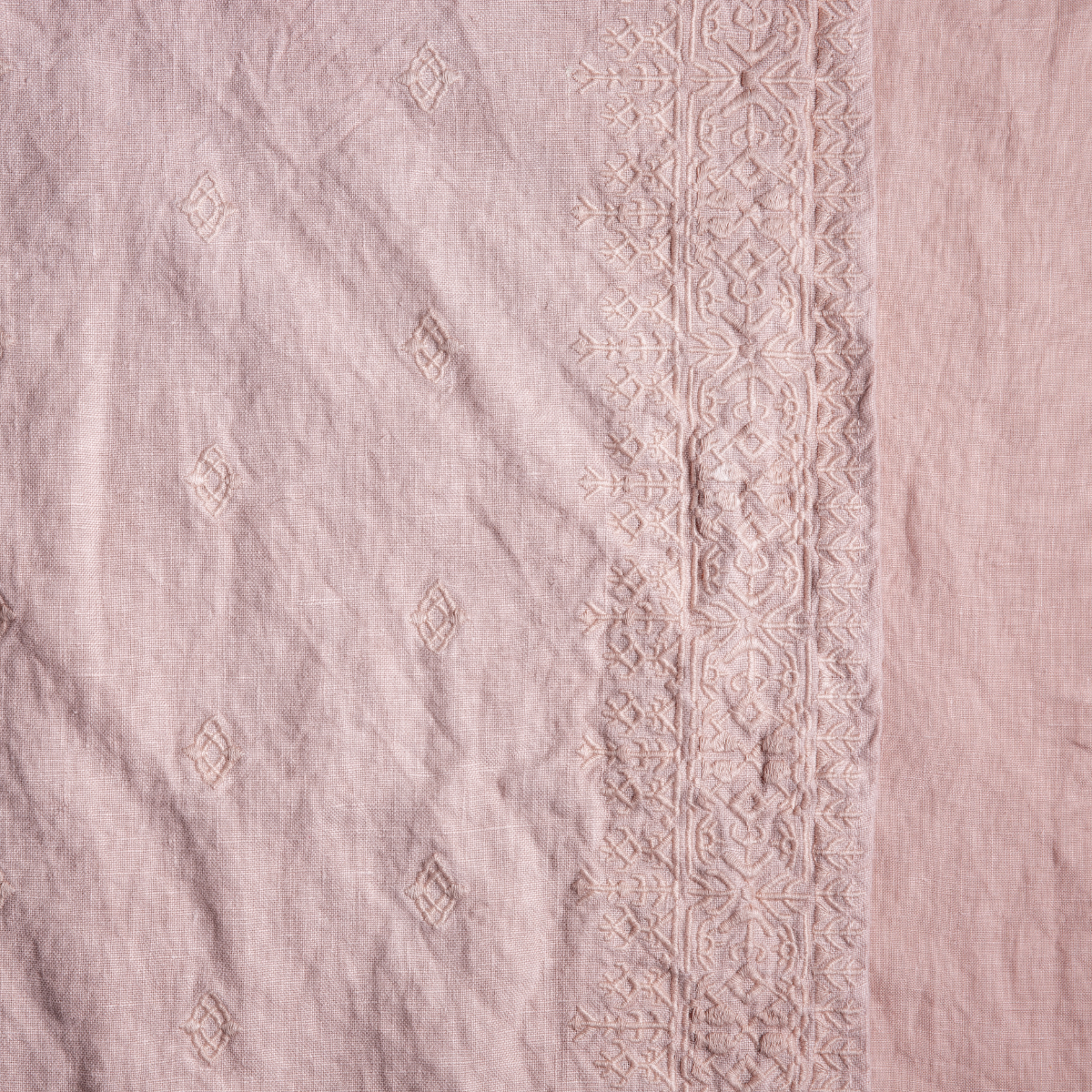Ines Baby Blanket | Rouge | A close up of embroidered midweight linen fabric in rouge, a mid-tone blush pink.