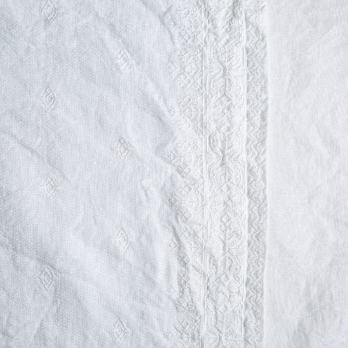Ines Baby Blanket | White | A close up of embroidered midweight linen fabric in classic white.