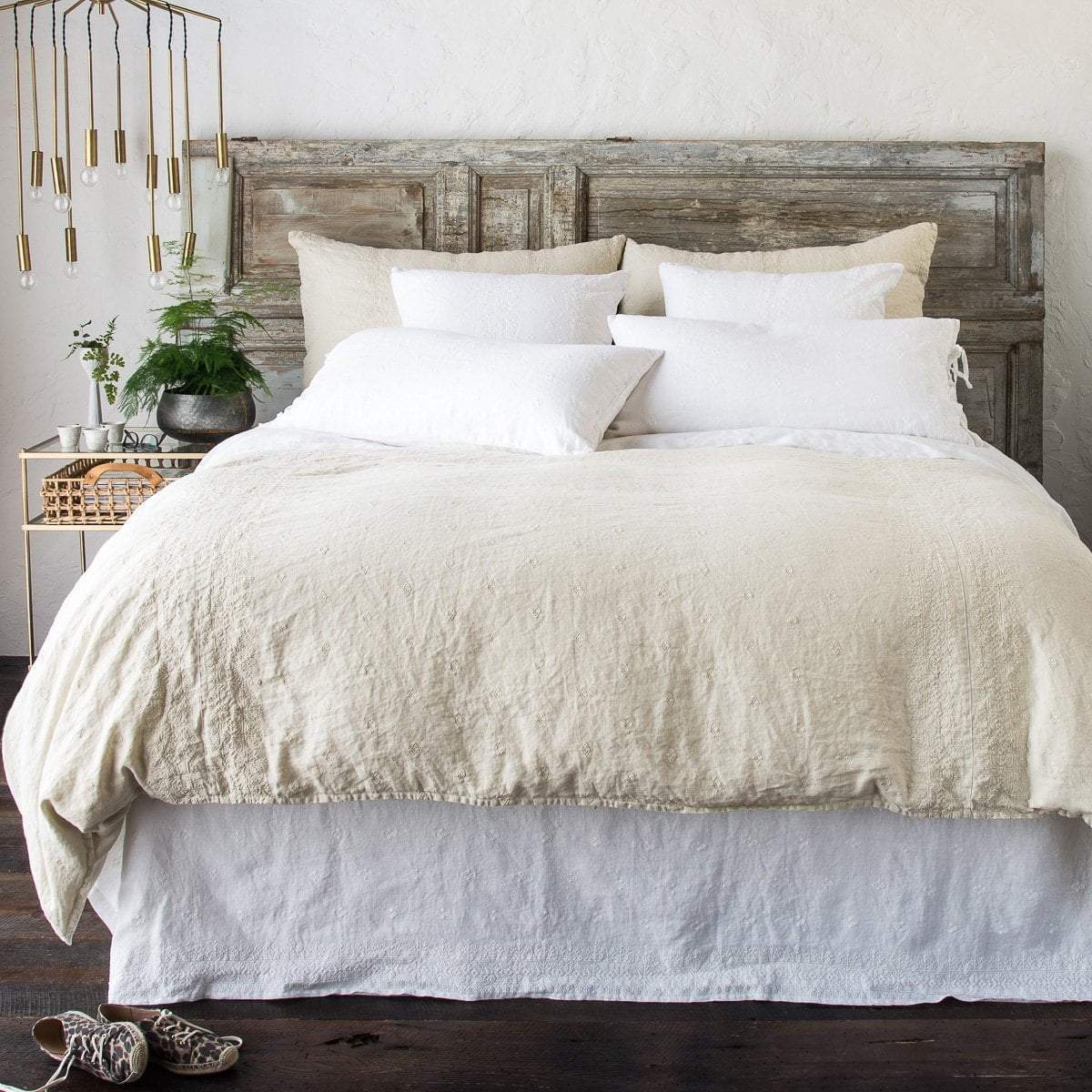 Parchment | Ines duvet cover, shams and bed skirt in parchemnt and white, against a distressed wood headboard and brass room accents - end of bed view.