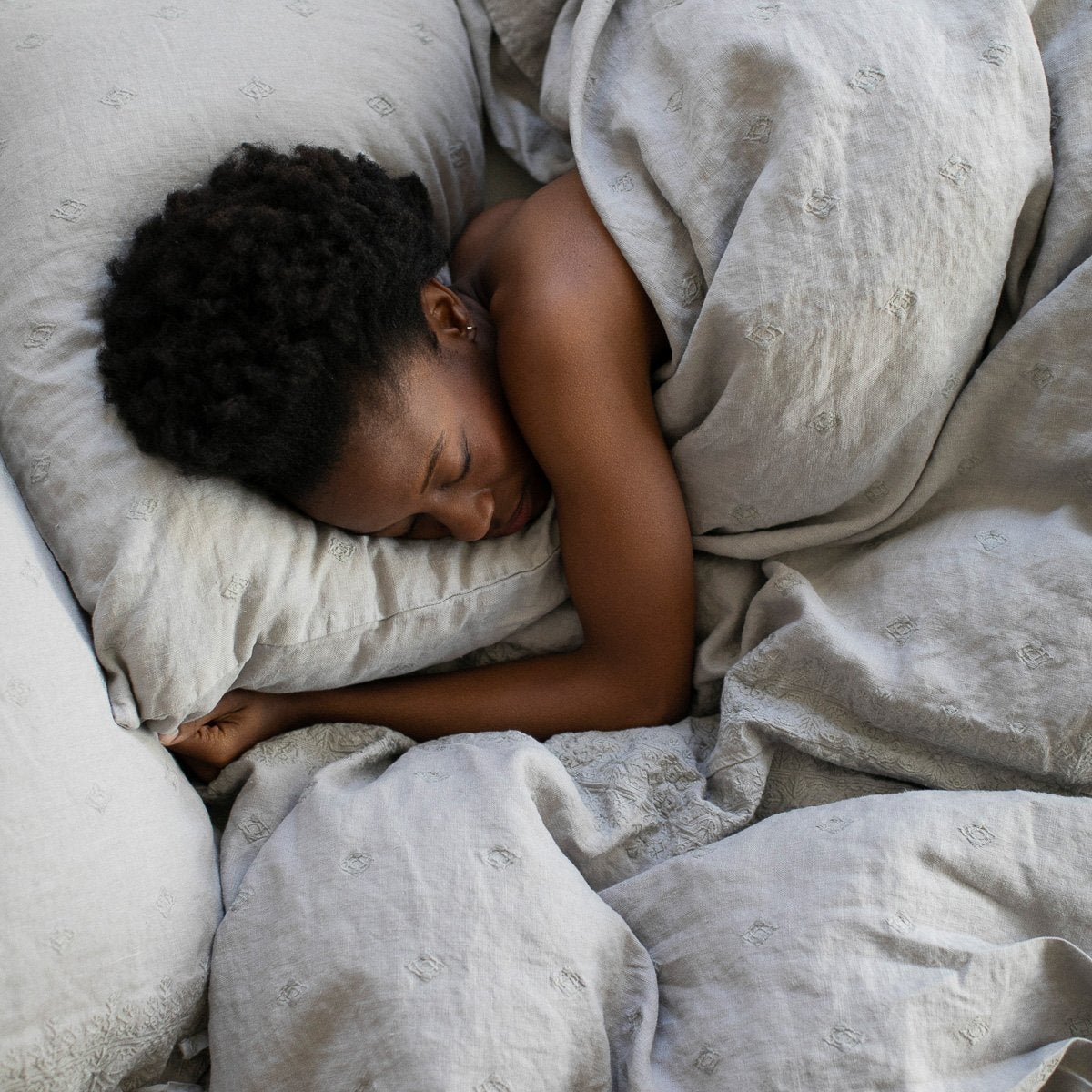 Ines Duvet Cover | Fog | Woman sleeping under Ines duvet in fog - overhead view.
