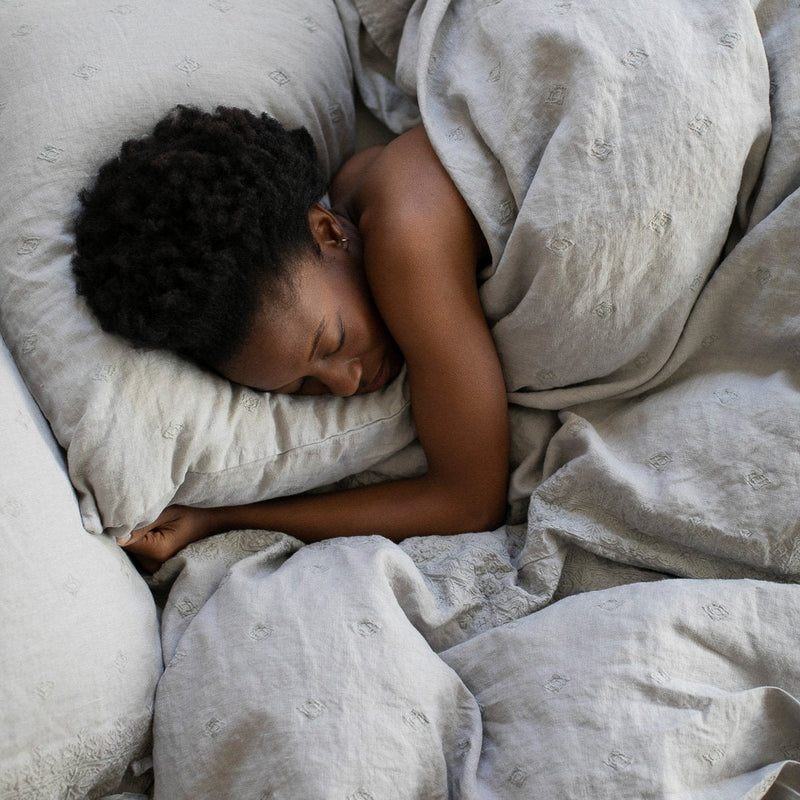 Ines Duvet Cover | Fog | Woman sleeping under Ines duvet in fog - overhead view.