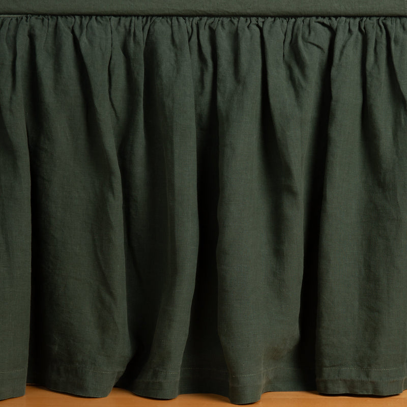 Juniper | linen bed skirt shown with matching fitted sheet, shot straight forward at the base of the bed with the skirt gently dusting the floor.