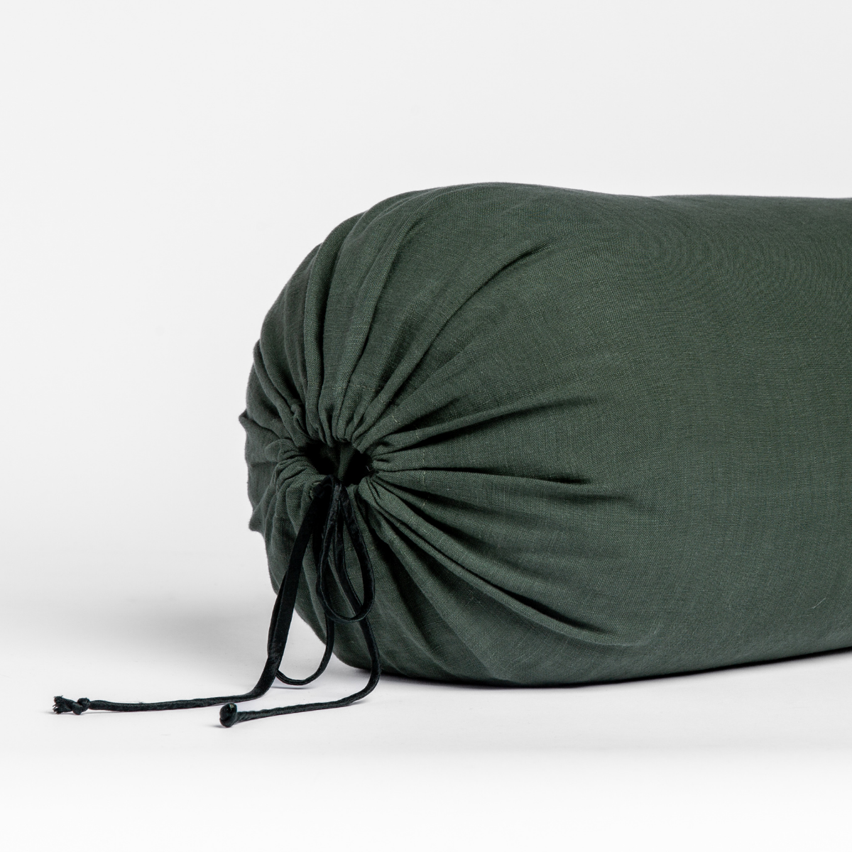 Linen Throw Pillow | Juniper | end of a bolster pillow shown cinched closed with satin ties against a white background.
