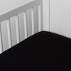 Corvino | linen crib sheet on the mattress shot slightly overhead into the corner of a white crib. against a white background.