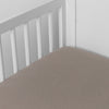 Fog | linen crib sheet on the mattress shot slightly overhead into the corner of a white crib. against a white background.