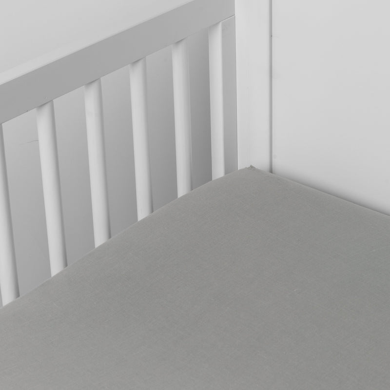 Mineral | linen crib sheet on the mattress shot slightly overhead into the corner of a white crib. against a white background.