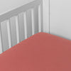 Poppy | linen crib sheet on the mattress shot slightly overhead into the corner of a white crib. against a white background.