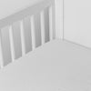 Winter White | linen crib sheet on the mattress shot slightly overhead into the corner of a white crib. against a white background.