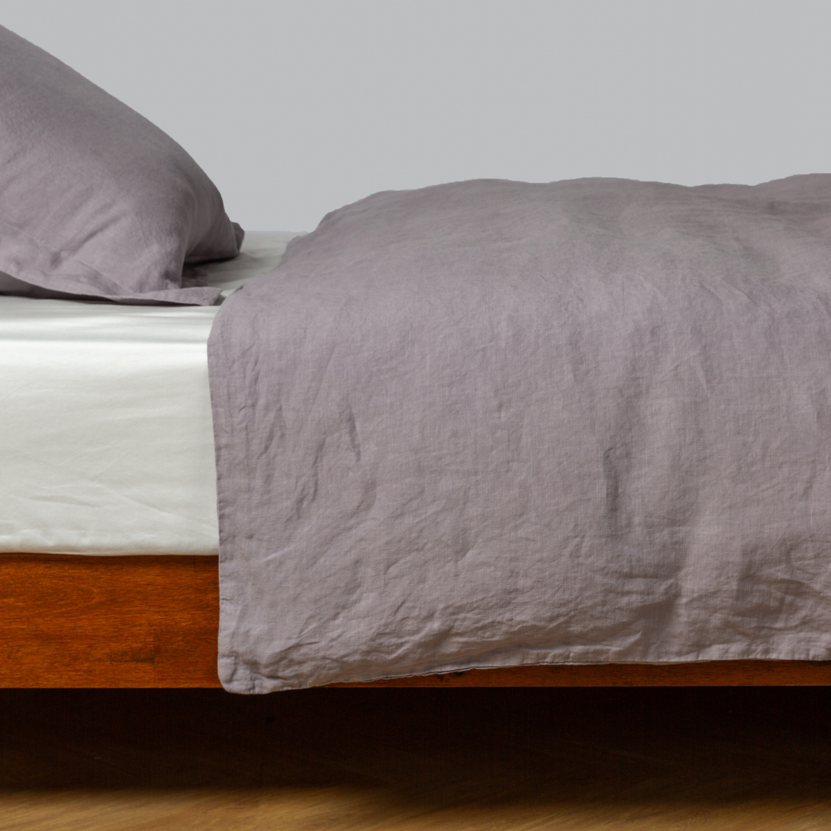 French Lavender | linen duvet cover shown with matching sham from the linen collection on a bed dressed with a winter white fitted sheet - side view.
