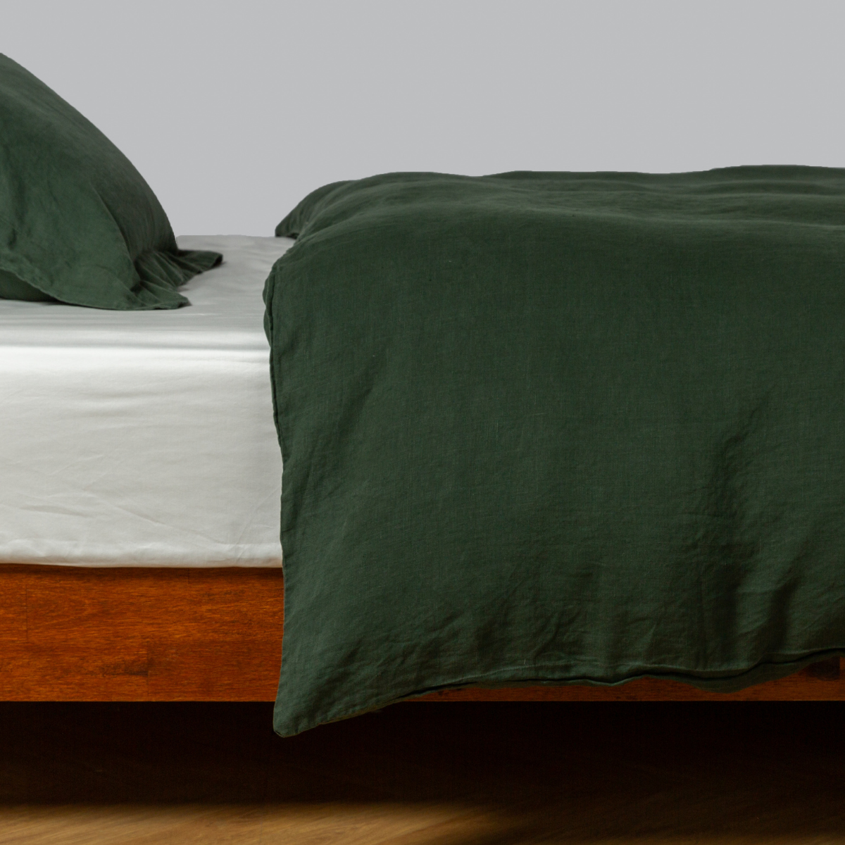 Juniper | linen duvet cover shown with matching sham from the linen collection shown on a bed dressed in a winter white fitted sheet - side view.