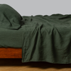 Juniper | linen fitted sheet with matching flat sheet and pillowcase shown on a bed from the side view.