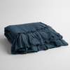 Linen Whisper Baby Blanket | Midnight | a folded linen with linen whisper ruffled blanket folded and positioned to show the ruffle detail against a white background and slightly overhead.