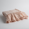 Linen Whisper Baby Blanket | Pearl | a folded linen with linen whisper ruffled blanket folded and positioned to show the ruffle detail against a white background and slightly overhead.