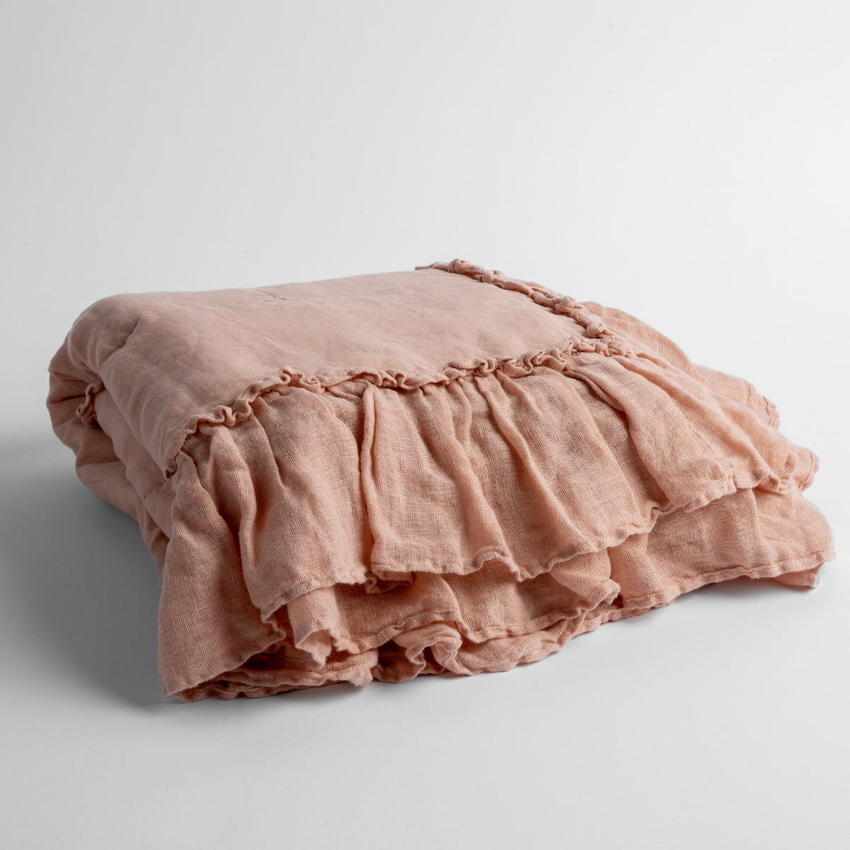Linen Whisper Baby Blanket | Rouge | a folded linen with linen whisper ruffled blanket folded and positioned to show the ruffle detail against a white background and slightly overhead.