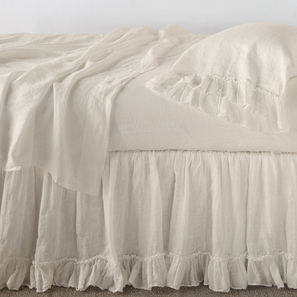Linen Whisper Bed Skirt | Parchment | bed skirt layered with monochromatic linen sheeting - side view.