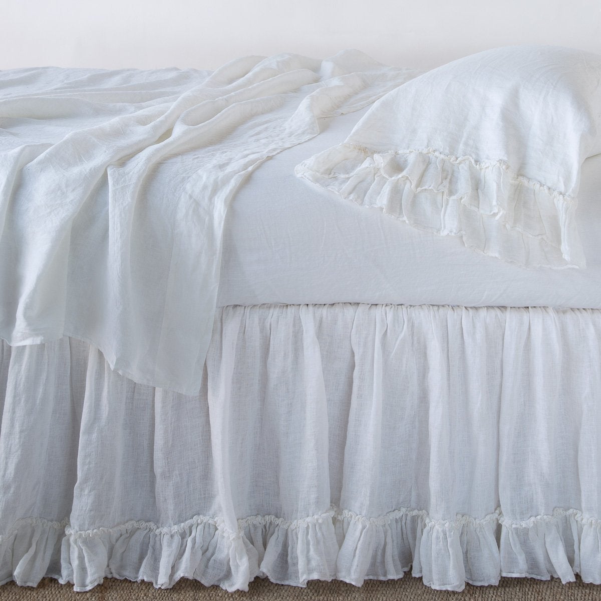 Linen Whisper Bed Skirt | White | bed skirt layered with monochromatic linen sheeting - side view.