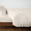 Linen Whisper Duvet Cover | Parchment | duvet cover folded back over a white fitted sheet, shown with matching sham against a plain background - side view.