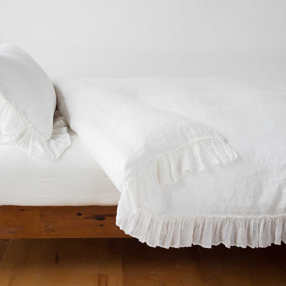 Winter White | Linen Whisper duvet cover folded back over a white fitted sheet, shown with matching sham against a plain background - winter white, side view.