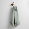 Linen Whisper Guest Towel | Eucalyptus | guest towel draped through a decorative brass towel ring, against a white wall.