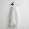 Linen Whisper Guest Towel | White | guest towel draped through a decorative brass towel ring, against a white wall.