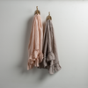 Two Linen Whisper guest towels, draped over decorative hooks against a white wall - pearl and fog.