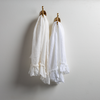Linen Whisper Guest Towel | pair of guest towels on decorative hooks mounted on a plain white wall.