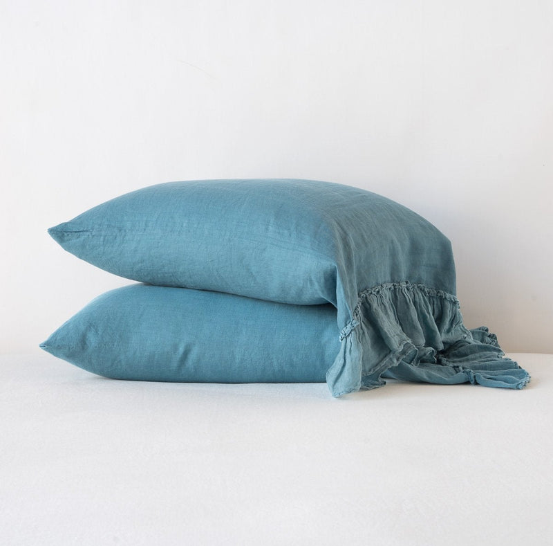 Linen Whisper Pillowcase (Single) | Cenote | Two sleeping pillows stacked at a slight angle against a plain background, showcasing ruffle trim detail - side view.